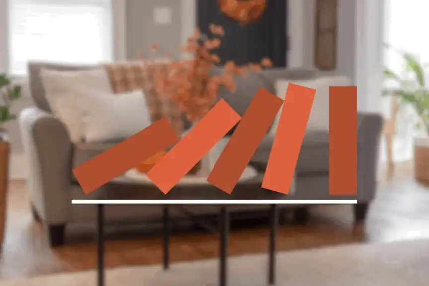 A graphic of five red rectangles resembling falling dominoes is overlaid on a blurred living room scene with a sofa and decorative pillows.