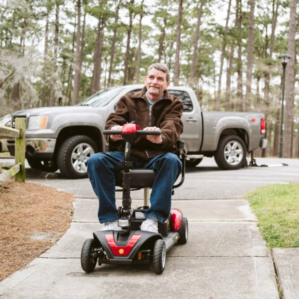a person using a 4-wheel golden technologies power scooter outdoors.