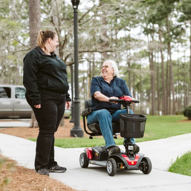 a person using a 4-wheel golden technologies power scooter in a park.