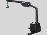 A black mechanical lift with a blue nylon strap and hook attachment for lifting objects, set against a plain gray background.