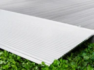 Close-up of a ribbed metal ramp on a green grass surface, showing the textured details of the ramp and the contrast with the grass.