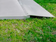 A metal accessibility ramp installed on a grassy area.