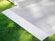 A white ramp with ribbed texture is set up over green grass, leading to a platform structure in the background.