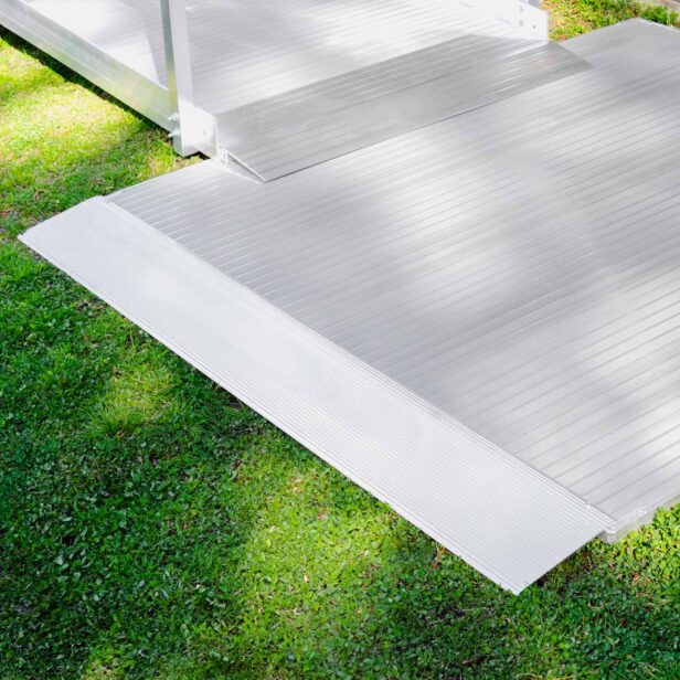 A white ramp with ribbed texture is set up over green grass, leading to a platform structure in the background.