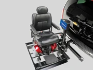 A black and red motorized wheelchair attached to a lift on the back of a black vehicle with a Chevrolet emblem.