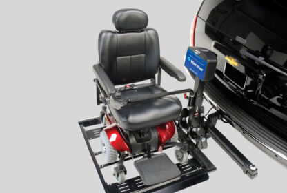 A black and red motorized wheelchair attached to a lift on the back of a black vehicle with a Chevrolet emblem.