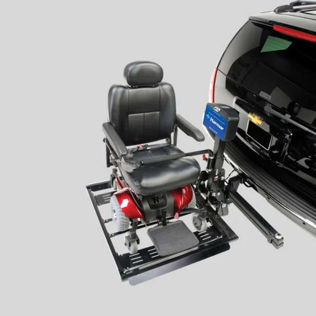 A black and red motorized wheelchair attached to a lift on the back of a black vehicle with a Chevrolet emblem.