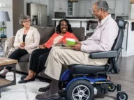 a person using a blue pride power chair in a living room.