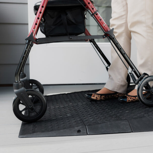 Person using a walking aid with a black mat underfoot near a door.
