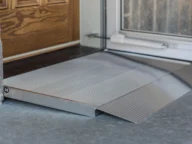 A metal accessibility ramp next to a door used to facilitate entry for wheelchairs.