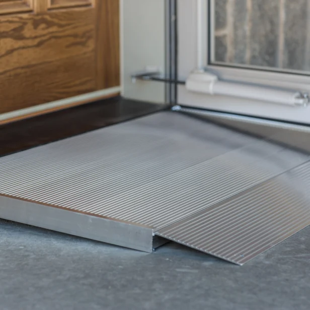 A metal accessibility ramp next to a door used to facilitate entry for wheelchairs.