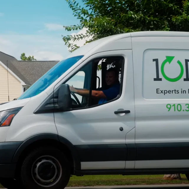 A white van with "101 Mobility" and a phone number displayed on the side is driving through a residential area with houses and trees in the background.