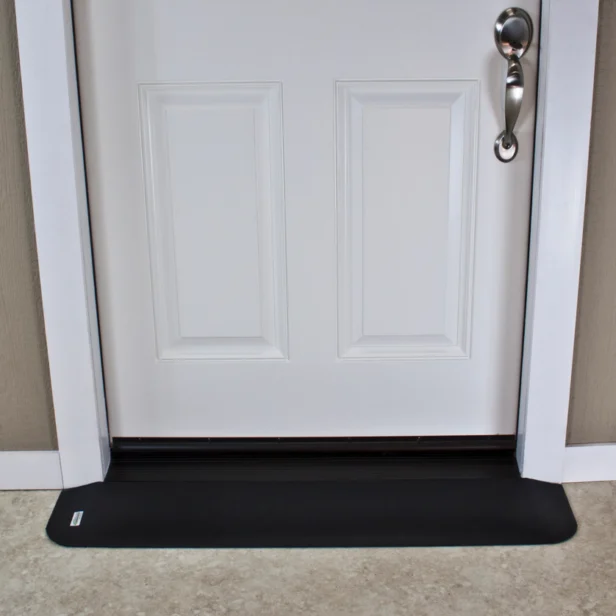 White door with a silver handle and a black draft stopper at the bottom, set against a beige wall and light-colored floor.