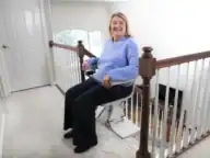 Woman seated on a Bruno Elan SRE-5000 stairlift with the seat swiveled toward the top landing