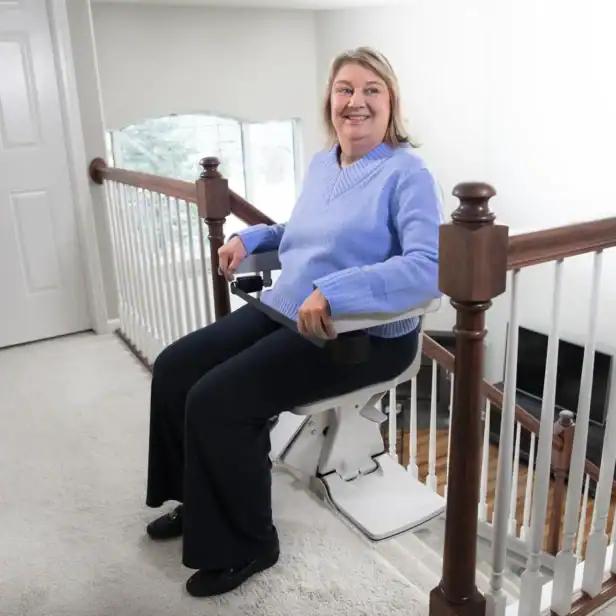 Woman seated on a Bruno Elan SRE-5000 stairlift with the seat swiveled toward the top landing