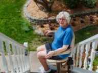a woman using a bruno elite outdoor stairlift.