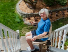 a woman using a bruno elite outdoor stairlift.
