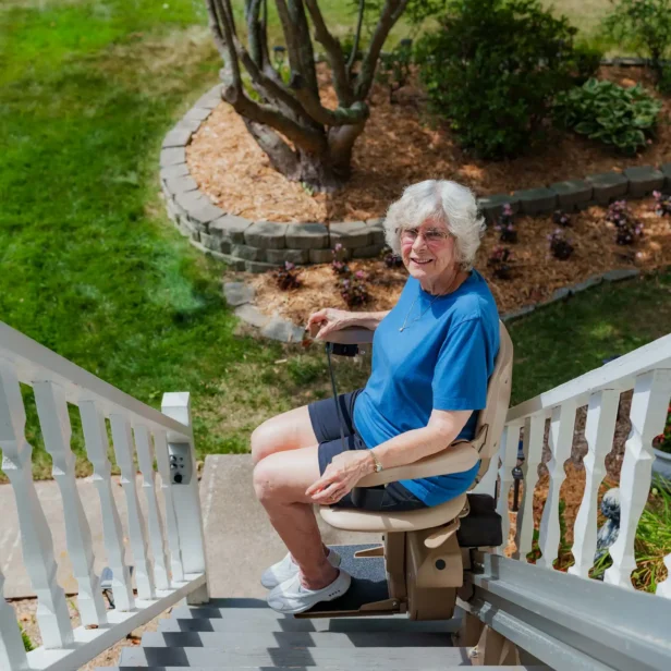 a woman using a bruno elite outdoor stairlift.