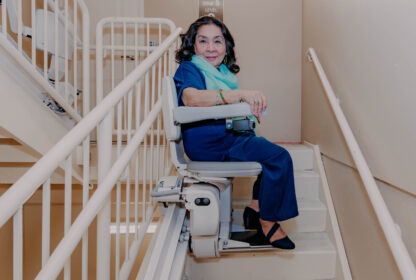 a woman using a bruno elite curved stairlift.