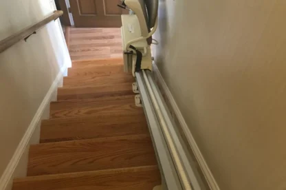 A stairlift installed along a wooden staircase providing assistance for individuals to move between floors.
