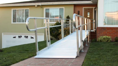 Aluminum wheelchair ramp leading from a brick pathway to the entrance of a house.