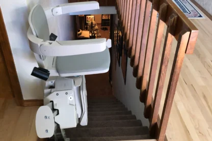 A stairlift is installed on the side of a wooden staircase in a house.
