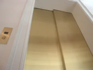 Closed gold elevator doors with a beige wall and a button panel on the left.