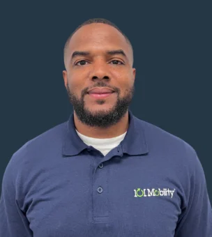 Man wearing a blue "LOI Mobility" polo shirt stands against a plain, dark background.