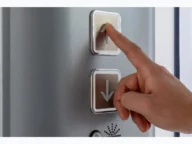 Finger pressing up button on an elevator control panel.