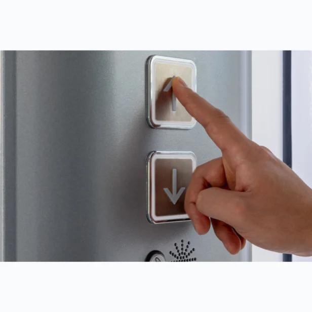 Finger pressing up button on an elevator control panel.