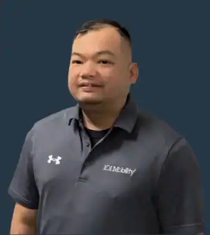 A man wearing a gray "IOC Mobility" polo shirt stands against a plain dark background, facing the camera.