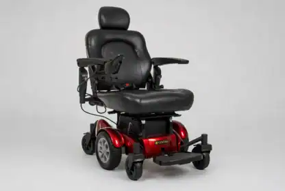 A black and red electric power wheelchair with padded seat, armrests, footrest, and four wheels, shown against a plain light background.
