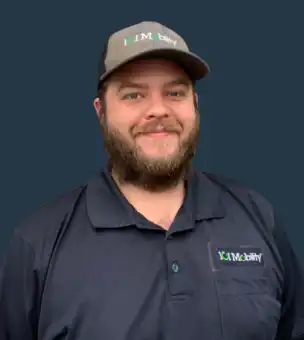 A bearded man wearing a black "101 Mobility" cap and polo shirt stands in front of a plain dark background, smiling at the camera.