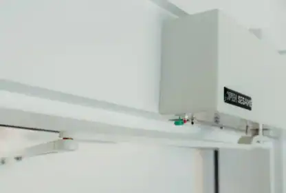 Close-up of an automatic door opener device labeled "Open Sesame" installed on a white doorframe.