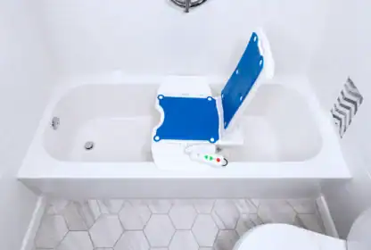 A bathtub with a blue and white bath lift chair and a remote control, designed to assist people with limited mobility.
