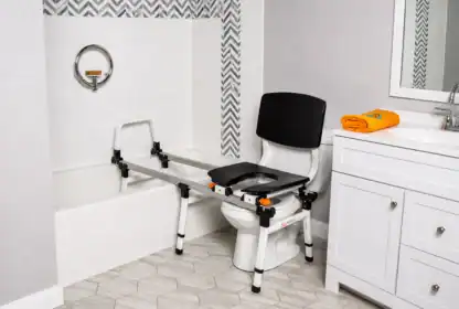 A bathroom features a transfer bench spanning a bathtub and toilet, designed to assist individuals with mobility challenges in safely moving between the two.