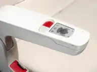 Close-up of a white electric vehicle charging station with a display screen, control buttons, and a slot for connecting a charging cable.