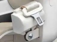 Close-up of a beige car seat belt buckle with the belt partially inserted into the locking mechanism.