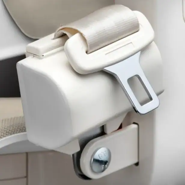 Close-up of a beige car seat belt buckle with the belt partially inserted into the locking mechanism.