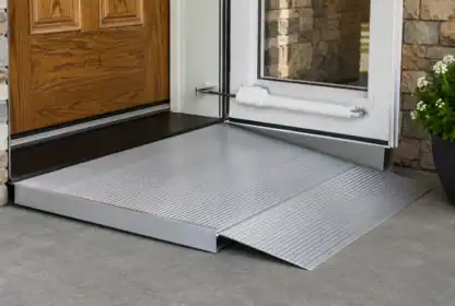 A metal wheelchair ramp is installed at a doorway, providing easy access from the concrete patio to the entrance of the building.