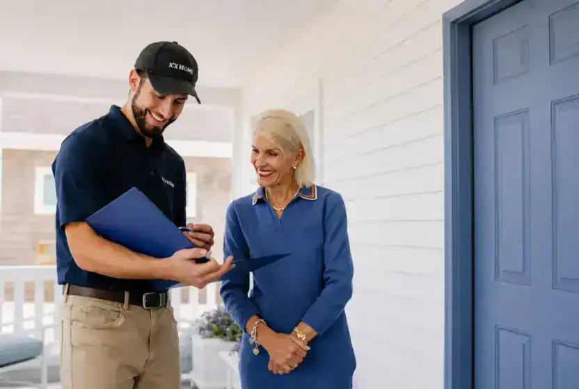A man in a uniform shows a document to a woman standing next to him on a porch beside a blue door.