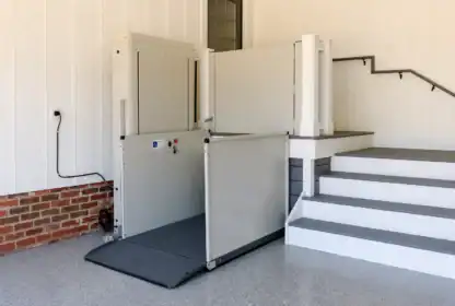 A wheelchair lift is installed next to a set of stairs, providing accessibility to a raised platform in a building’s interior.
