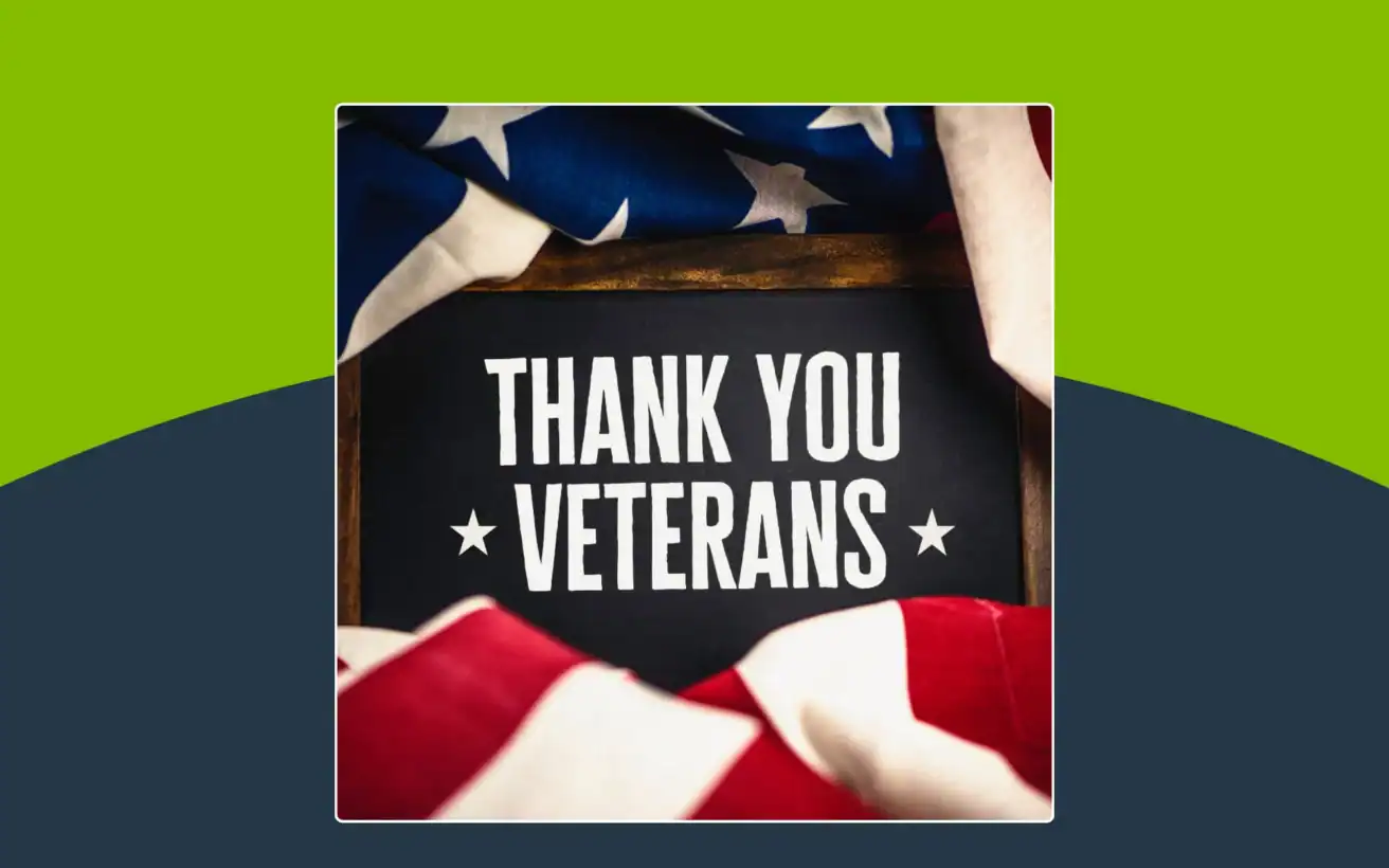 A sign reading “Thank You Veterans” is framed by a folded American flag, with a green and dark blue background.