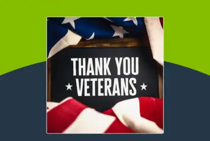 A sign reading “Thank You Veterans” is framed by a folded American flag, with a green and dark blue background.