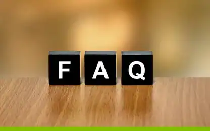 Three black blocks with white letters spell “FAQ” on a wooden surface with a blurred brown background.