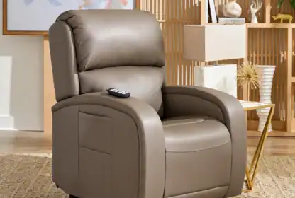 A brown leather recliner with a remote on the armrest sits on a beige rug in a modern, well-lit living room with decorative accents.