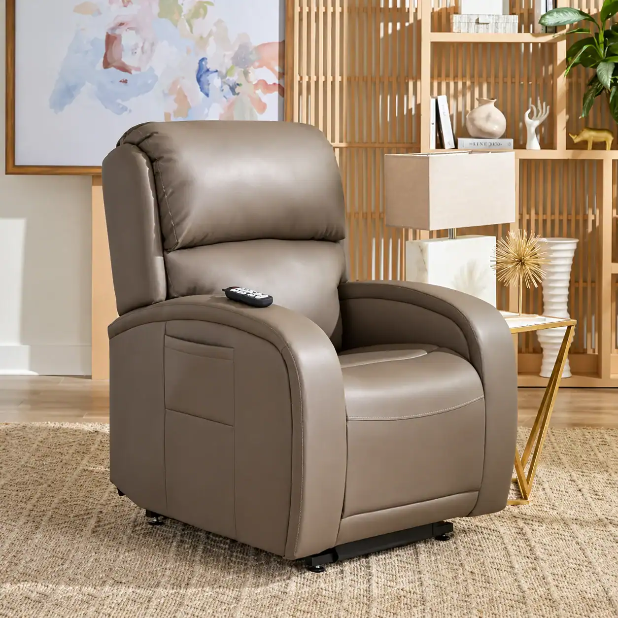 A brown leather recliner with a remote on the armrest sits on a beige rug in a modern, well-lit living room with decorative accents.