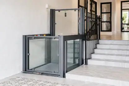 A residential wheelchair lift is installed next to a staircase, providing accessible entry between two levels inside a modern home.