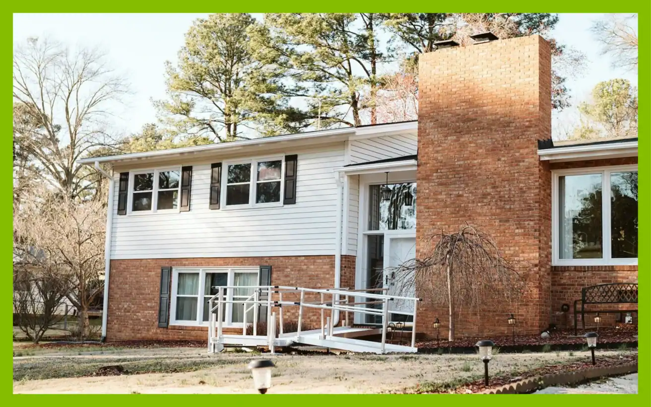 A split-level brick and white-sided house featuring a wheelchair ramp leading to the front entrance.