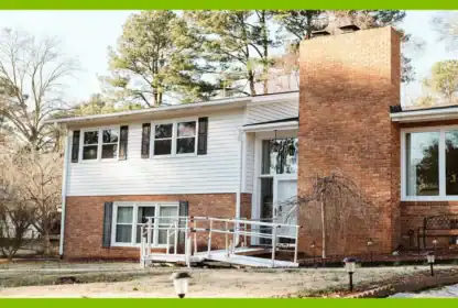 A split-level brick and white-sided house featuring a wheelchair ramp leading to the front entrance.